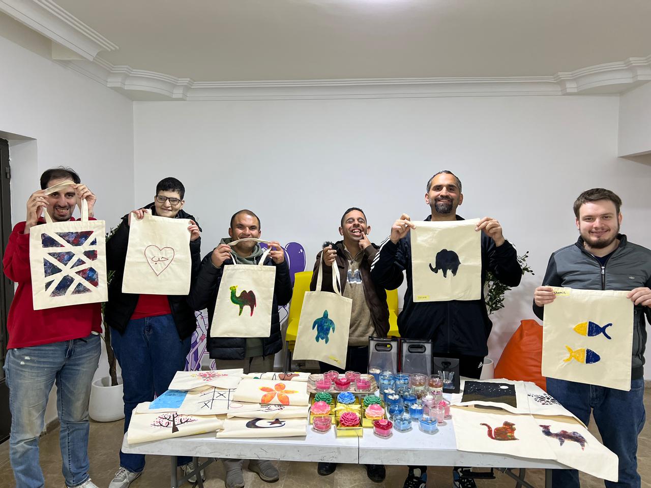 Be Positive participants holding hand-painted tote bags they created in a workshop.